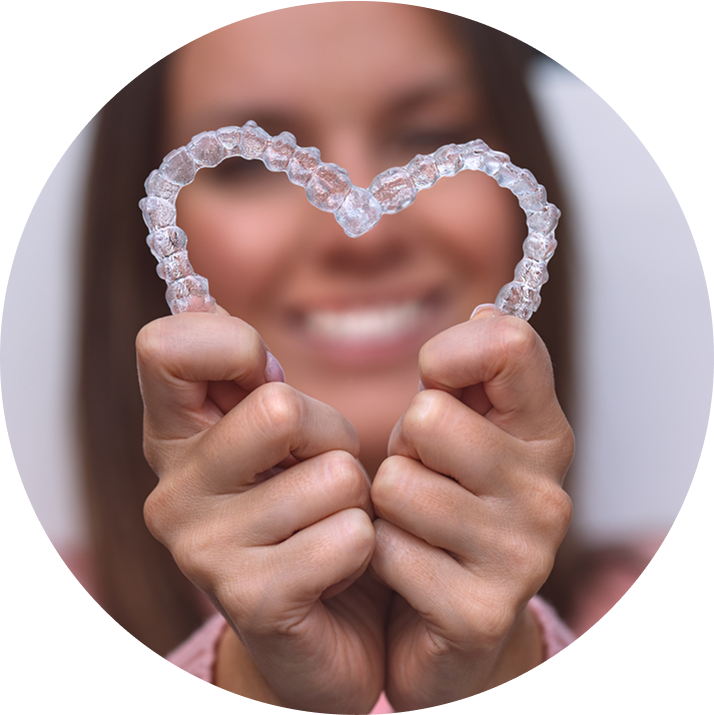 Close Up Of Smiling Woman Making Heart Shape Out Of Clear Aligners