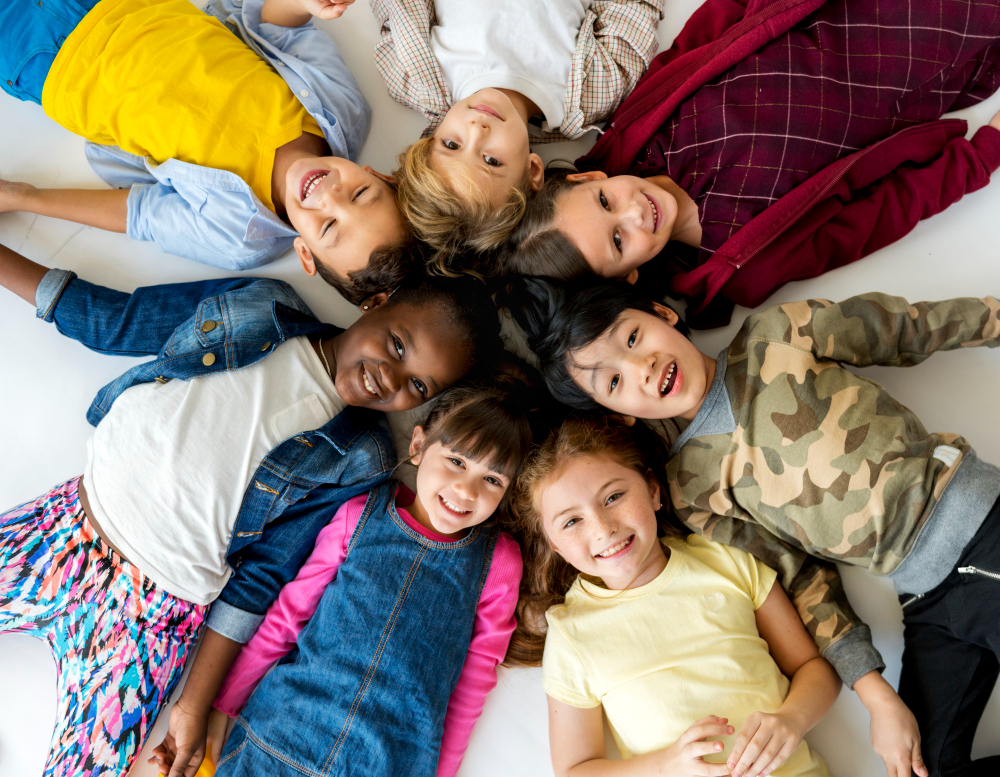 Group Of Smiling Children Laying In A Circle Looking Up