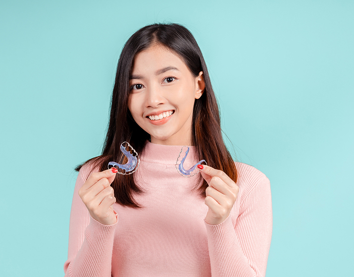 Smiling Woman Holding Two Retainers