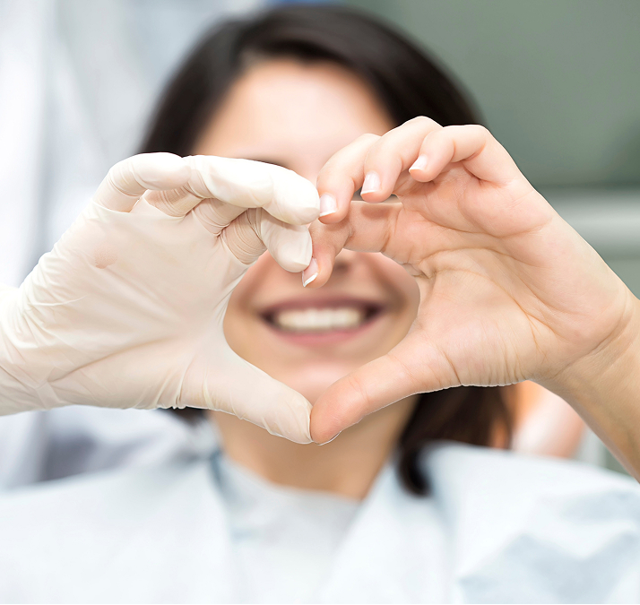 Smiling Woman And Orthodontist Making Heart Shape With Hands