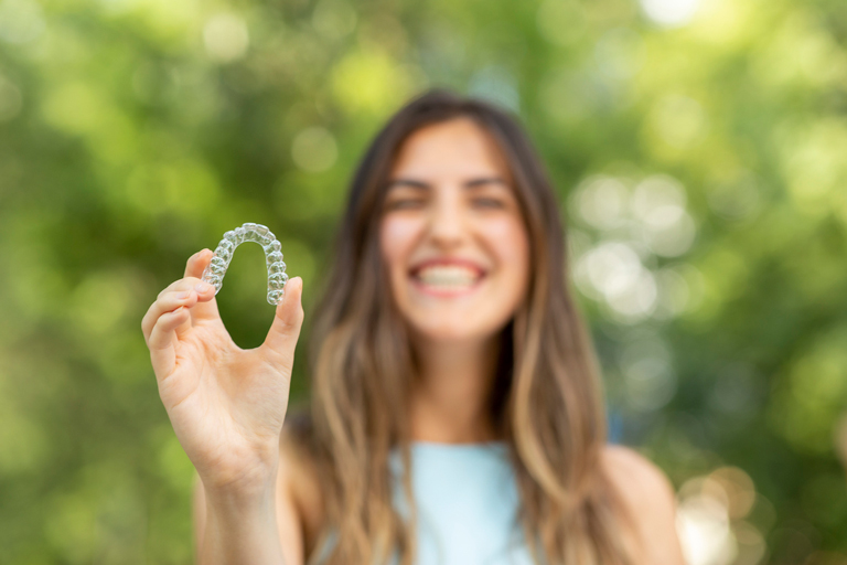 Smiling Woman Holding Clear Aligner