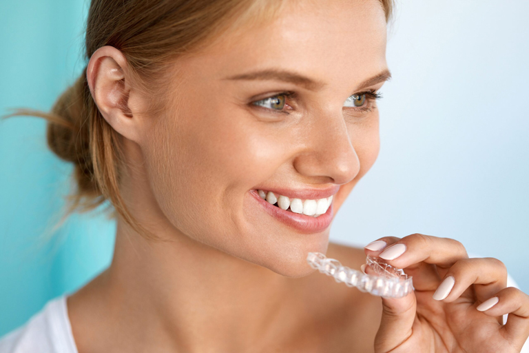 Smiling Young Woman Inserting Clear Aligner Scaled