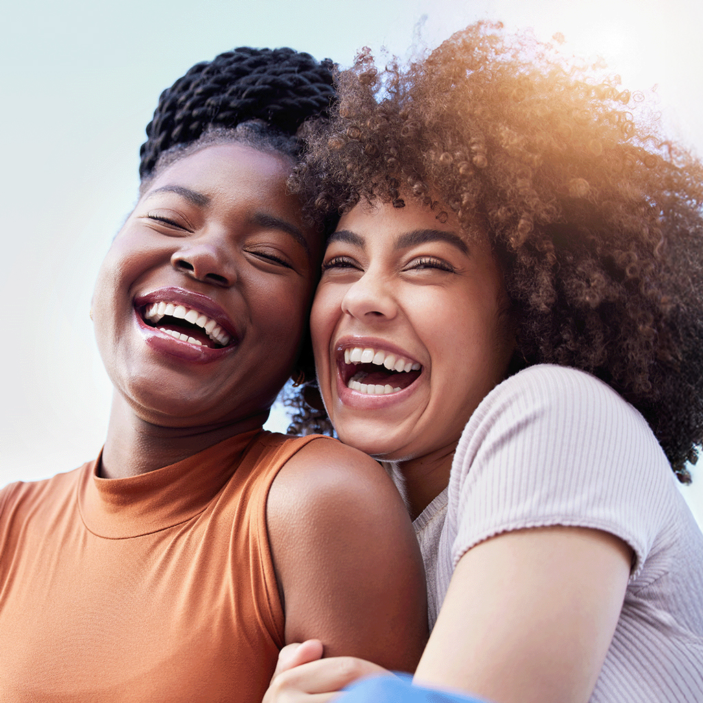 Two Smiling Women Hugging Each Other