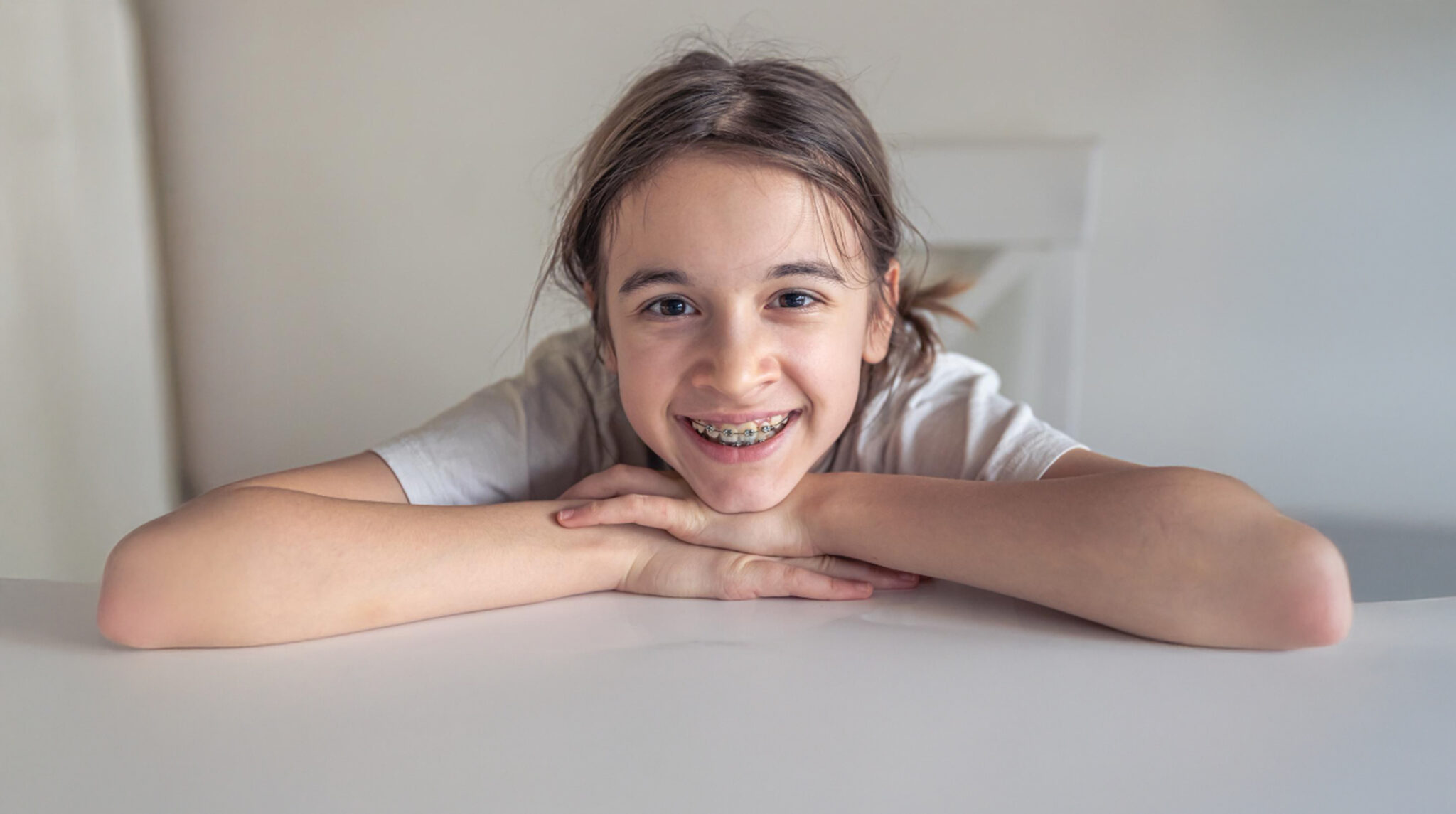 A Teen with braces smiling on a white table