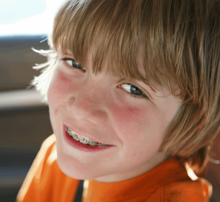 Child with braces smiling in an orange t-shirt