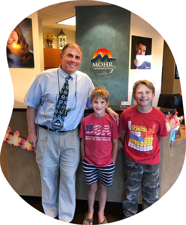 Orthodontist Dr. Mohr smiling with two young patients at Mohr Orthodontics
